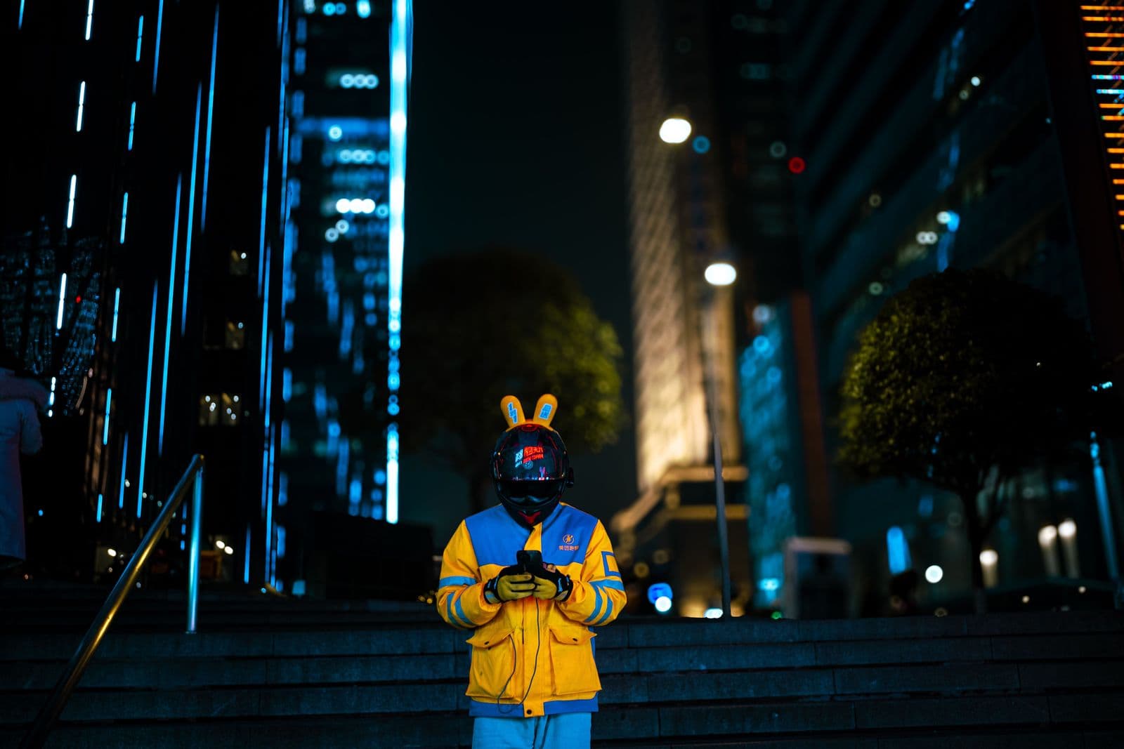 A delivery rider on a city street lit by neon signs at night