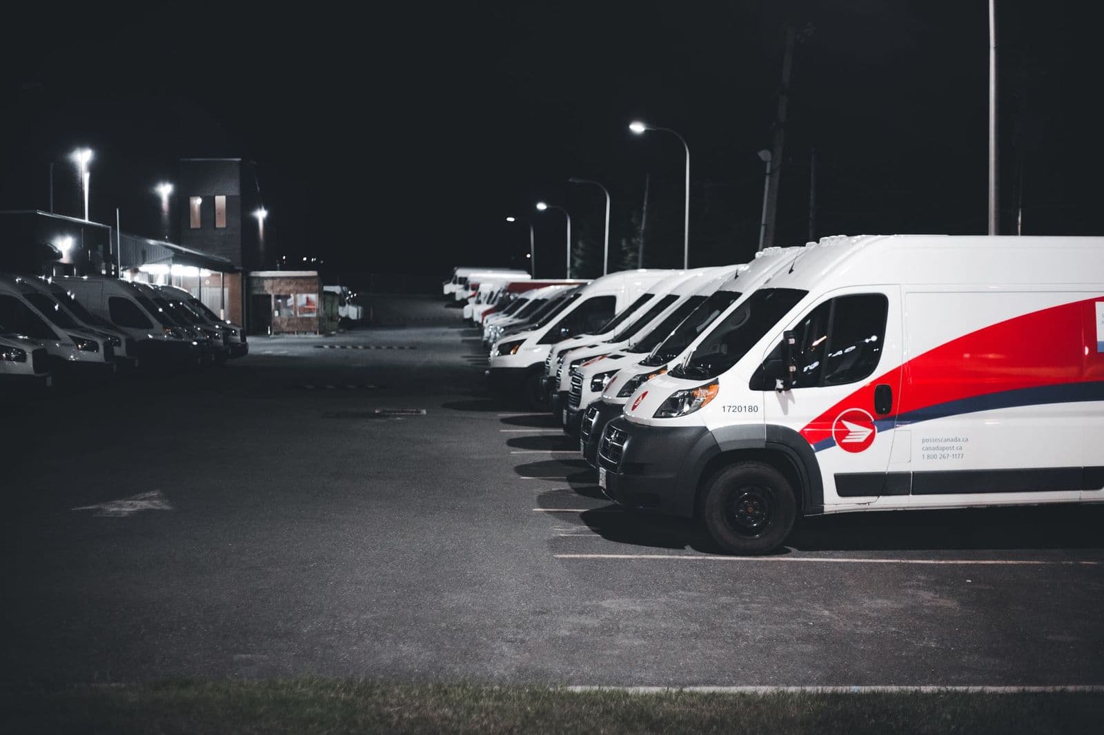 A fleet of vans parked in a depot lot before dawn