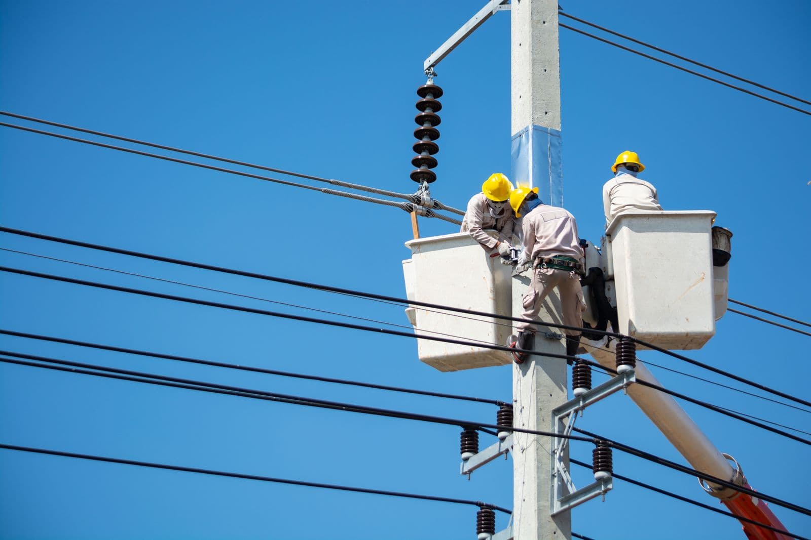 A utility crew working from elevated platforms on overhead power lines