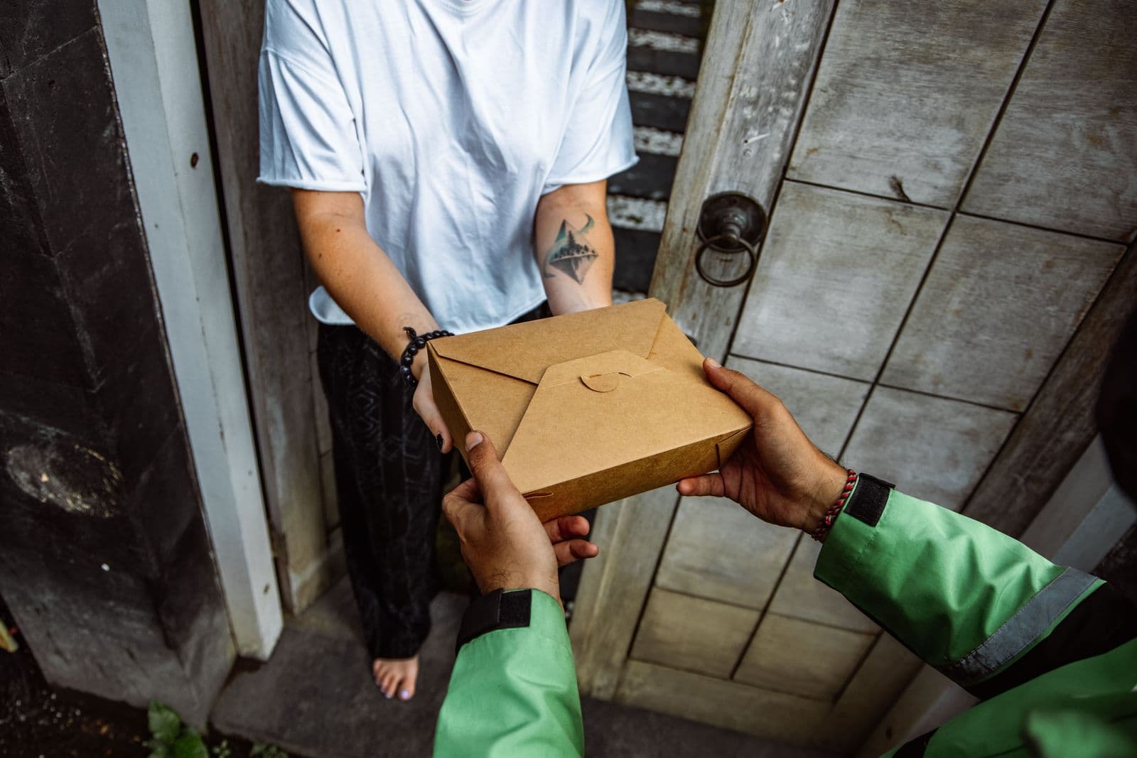 A delivery driver handing a parcel to a customer at their door