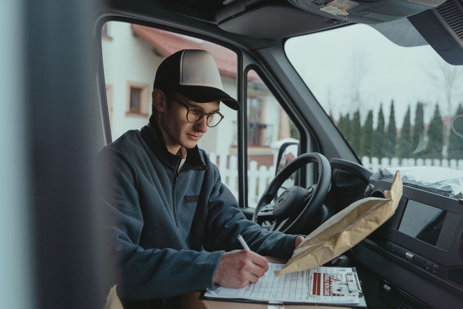 A courier recording delivery details in the cab of a parcel van