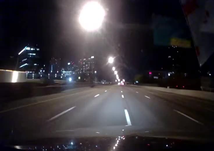 Road-facing Monarch camera at night on a city arterial, lane markings and streetlights picked out ahead of the vehicle