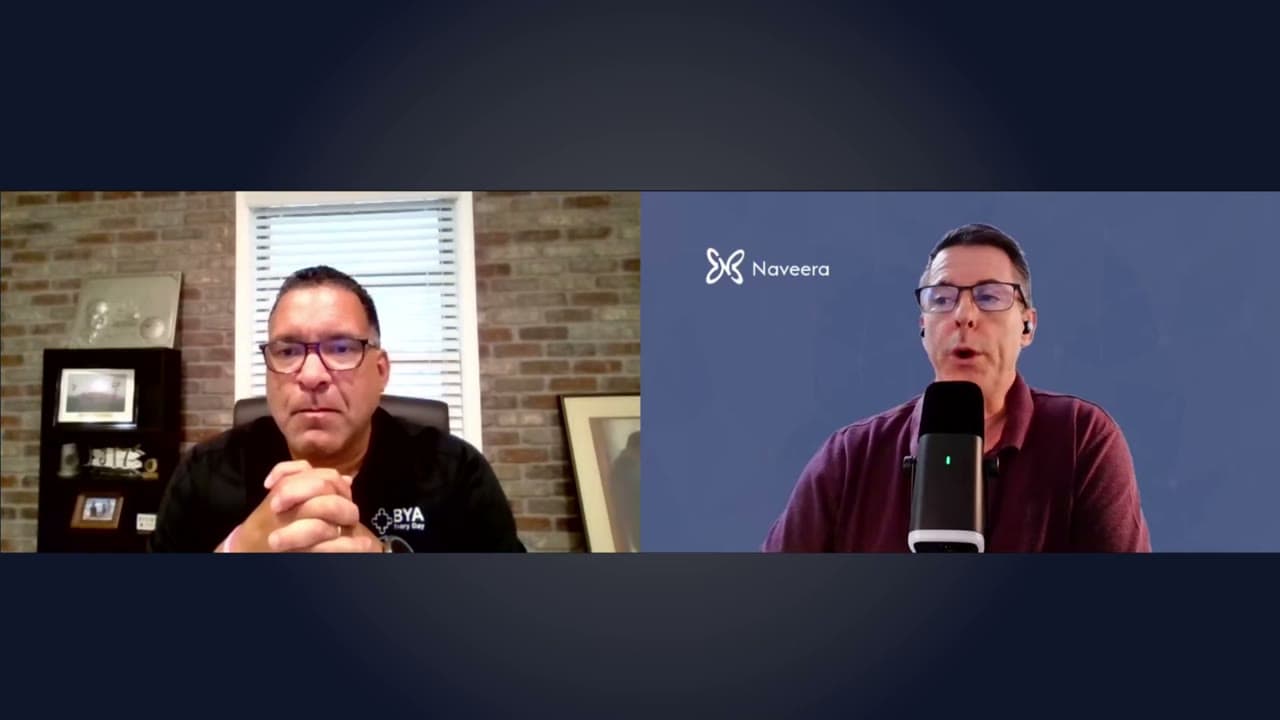 A video call in two panels: Phil Wilkins at his desk in front of a brick wall, and Jeff from Naveera at a microphone against a blue Naveera background.