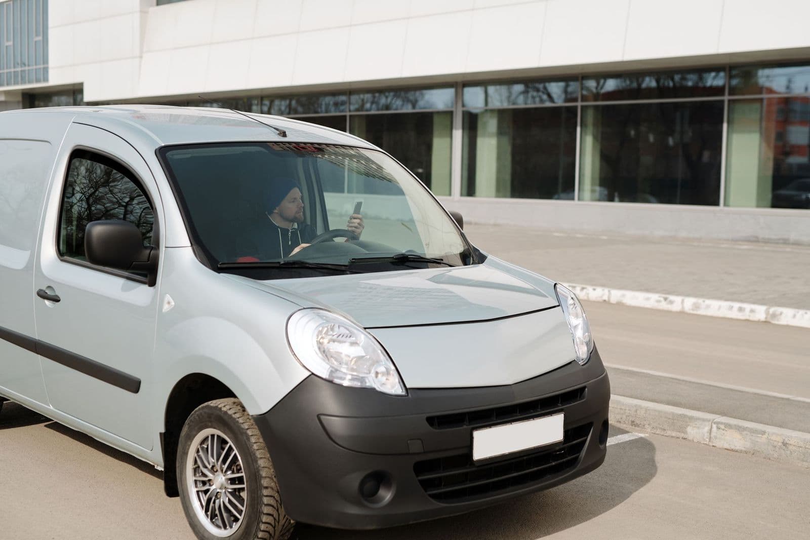 A white transport van parked outside a modern medical facility