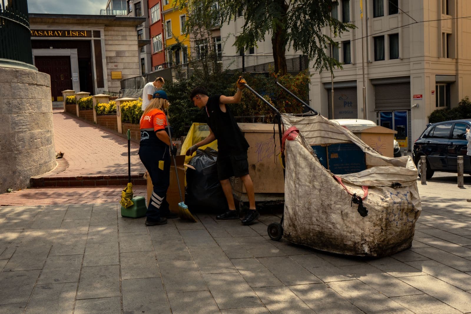 Two sanitation workers collecting waste on a city street