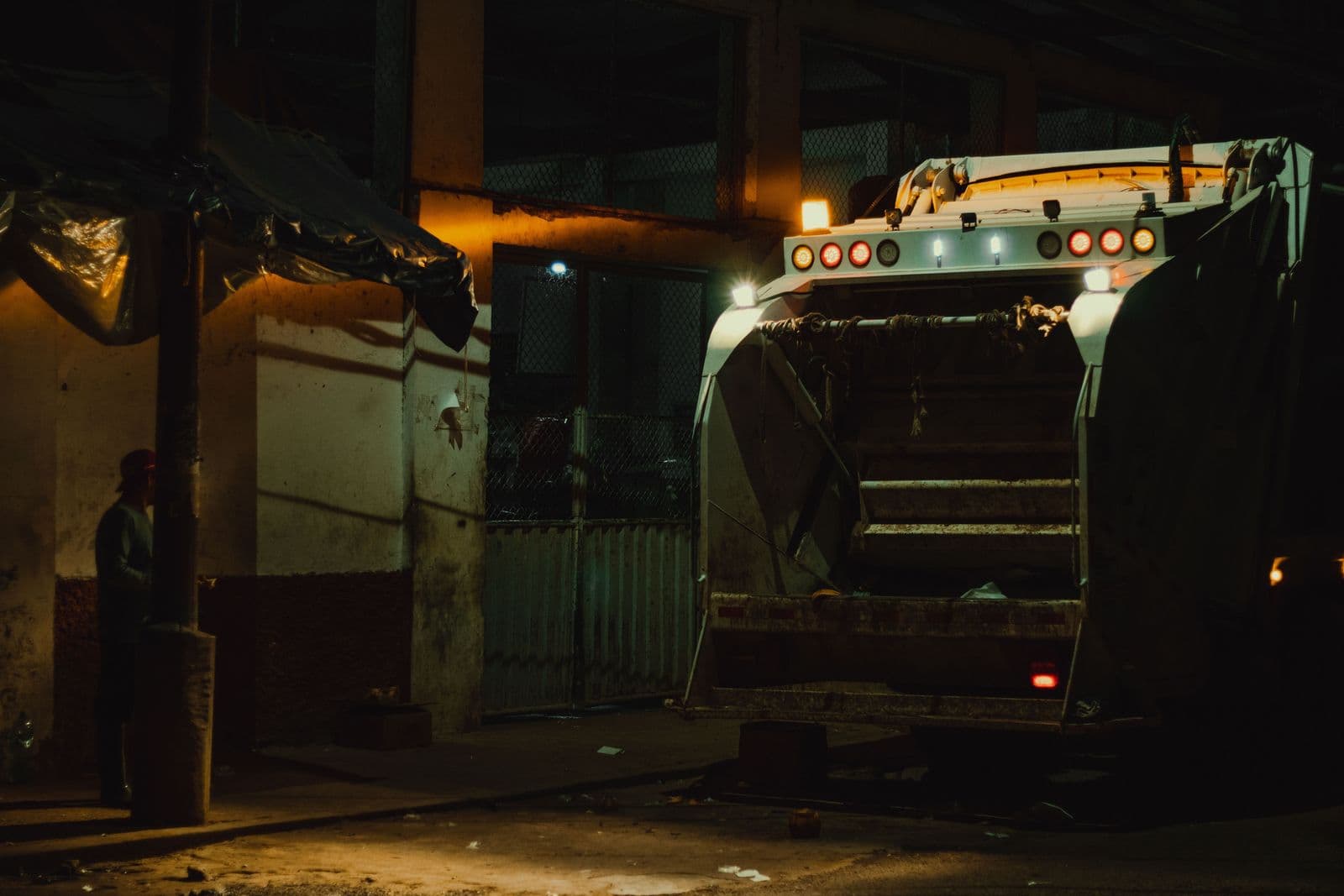 A refuse truck working under street lights before dawn