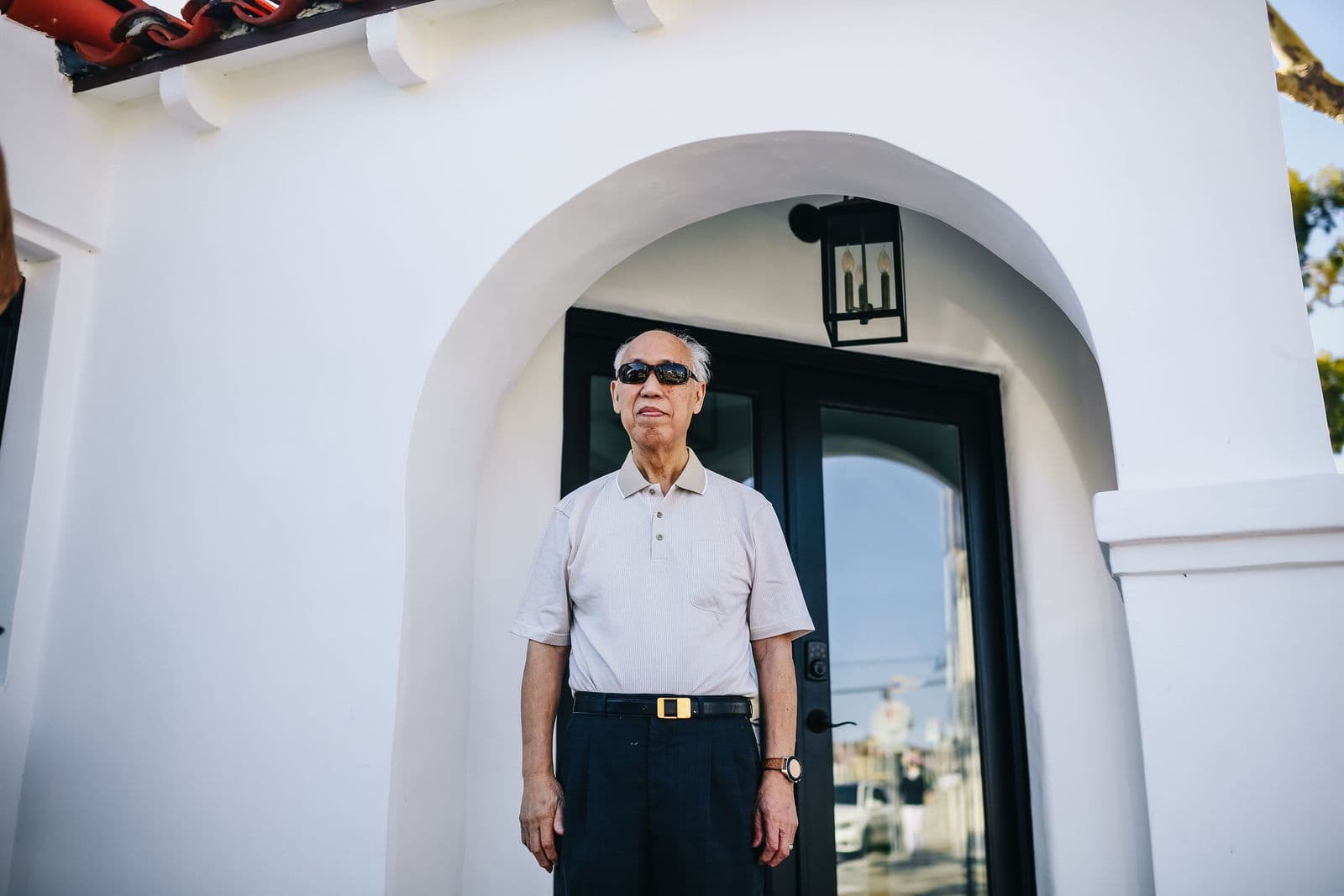 An older man waiting at the front door of his home, ready to be collected
